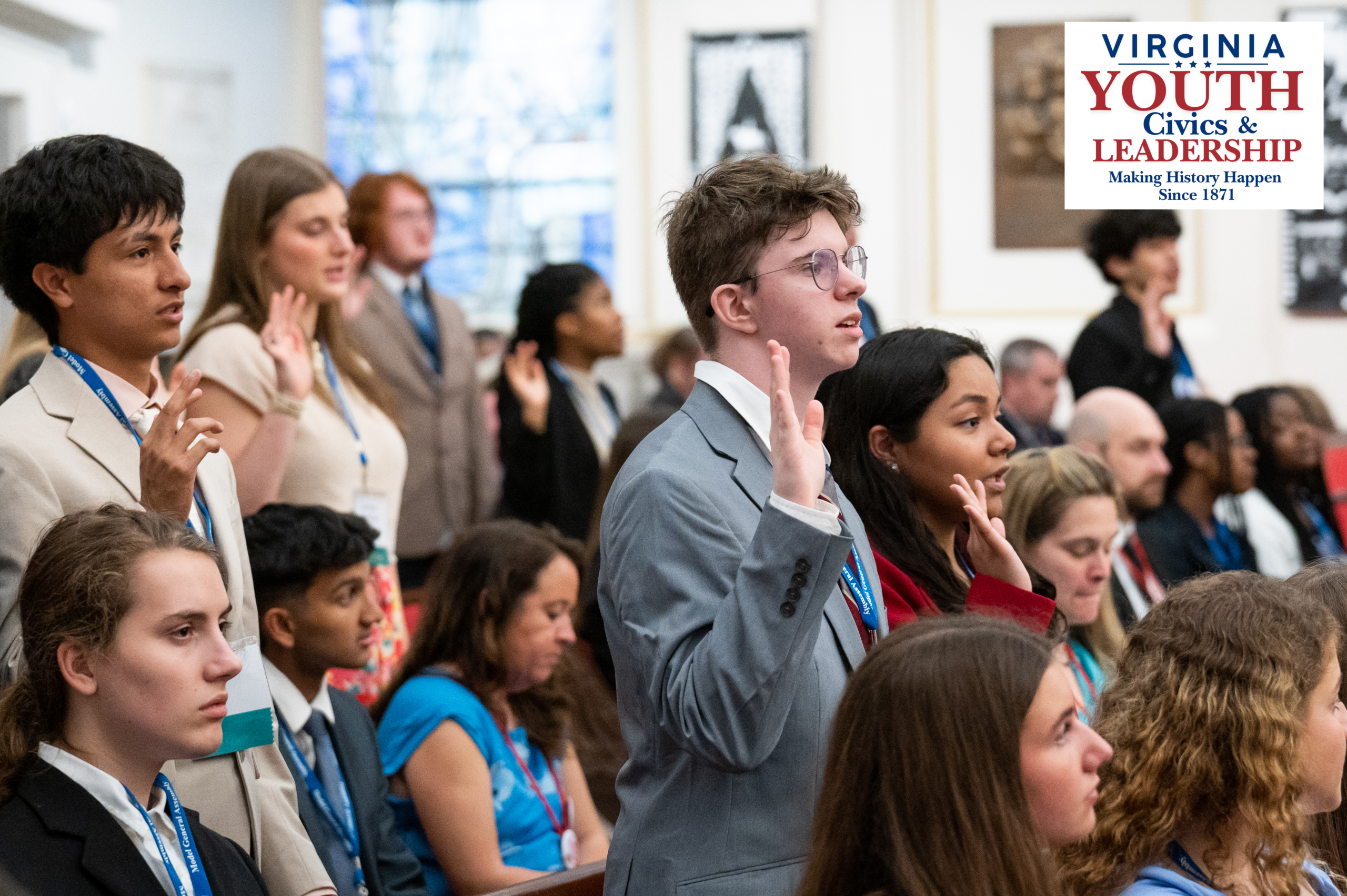 Young adults in professional attire raising their right hands to take an oath, featuring the Virginia Youth Civics & Leadership logo with the tagline 'Making History Happen Since 1871'.