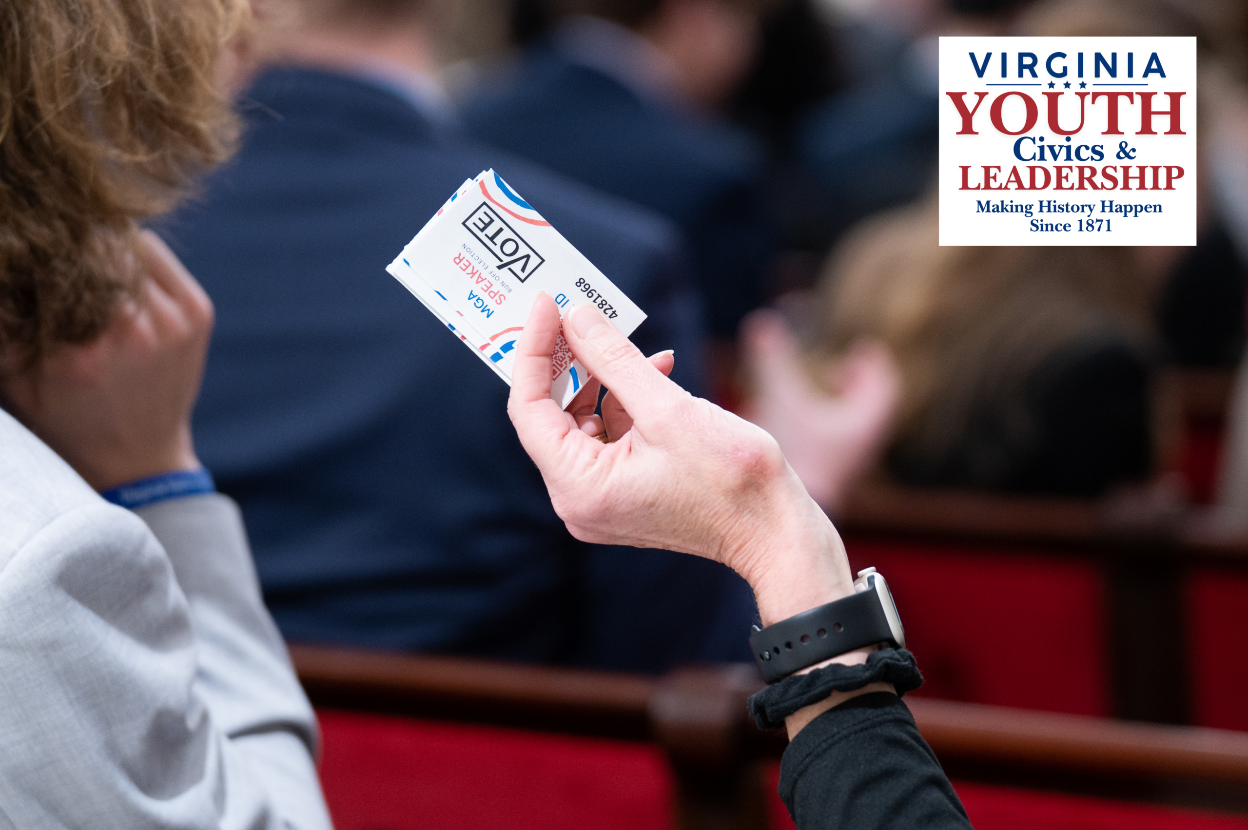 A hand holding up a voting card that reads 'VOTE MGA SPEAKER RUN OFF ELECTION', featuring the Virginia Youth Civics & Leadership logo.